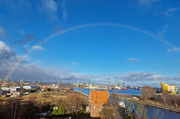 Gdansk on a sunny day with rainbow. Big cranes and dock at the shipyard. city is located right by sea.