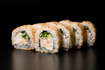 Sushi rolls california with snow crab, cream cheese, cucumber, sesame seeds on dark background.