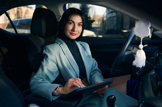 Confident Portrait Of A Caucasian Middle-aged, Successful Business Woman, Female Boss, Executive Director, Supervisor, Sales Manager With A Digital Tablet, Looking At Camera From A Modern Car Interior