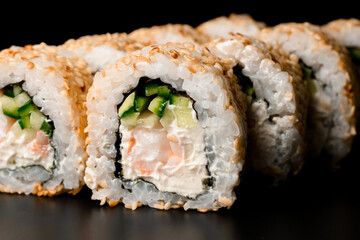 Close-up view on sushi rolls california with snow crab, cream cheese, cucumber, sesame seeds.
