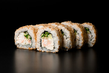 Tasty sushi rolls california with snow crab, cream cheese, cucumber, sesame seeds on dark background.