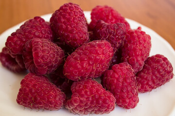 Ripe juicy red raspberries in a plate, close up macro. Healthy eating concept.