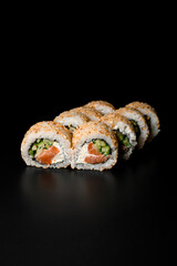 view on sushi rolls california with smoked salmon, cream cheese, cucumber, sesame seeds on dark background.