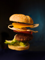Floating burger in blue background, all ingredients lettuce meal, tomato, onion, bread, american,style, fall, cheese,