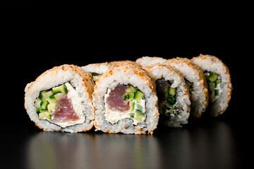 delicious sushi rolls california with salmon, cream cheese, cucumber, sesame seeds on dark background.