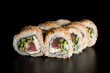 tasty sushi rolls california with salmon, cream cheese, cucumber, sesame seeds on dark background.