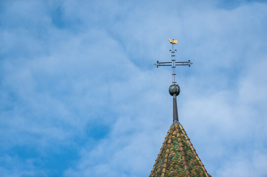 Detail Kirchturm mit Kreuz und Wetterhahn vor blauem Himmel
