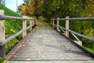 Obraz premium Wooden bridge for pedestrians next to a road in the countryside in autumn, Autumn landscape