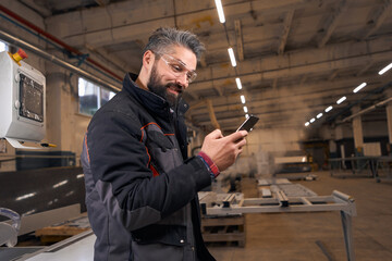 Portrait of worker holding mobile phone at work