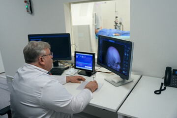 Fototapeta na wymiar Experienced doctor sits in front of monitors of diagnostic equipment