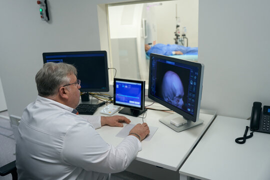 Experienced doctor sits in front of monitors of diagnostic equipment
