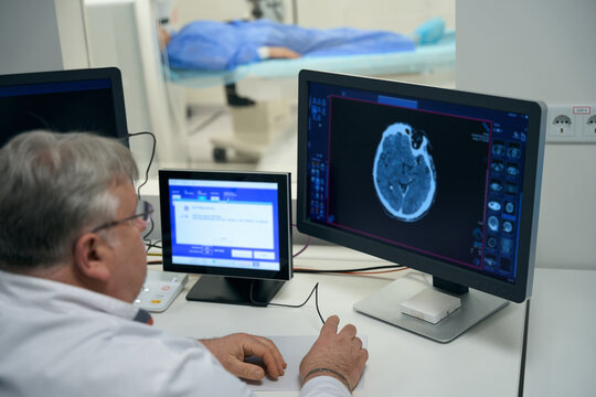 Elderly doctor performs MRI diagnostics of brain in modern clinic