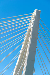 Obraz premium a side on image of a white concrete bridge pillar and cables against blue skies 