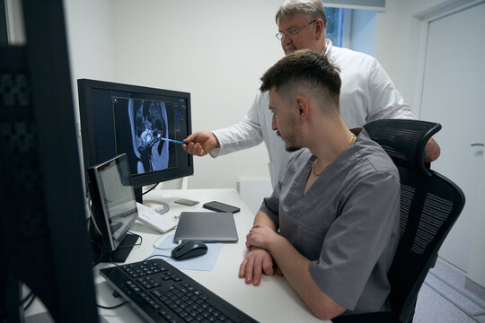 Two doctors examine the results of MRI on the monitor