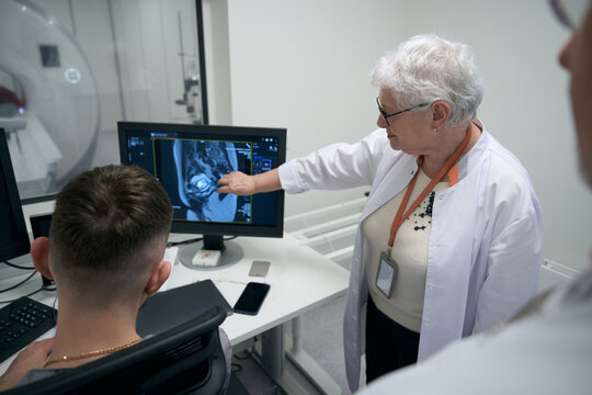 Employees of diagnostic department, elderly woman and men, perform MRI procedure
