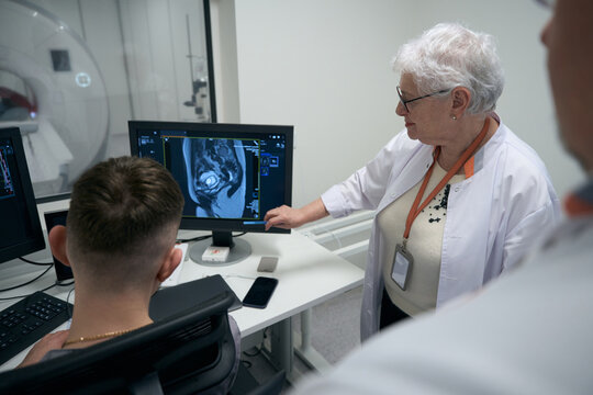 Colleagues diagnosticians, an elderly woman and men, perform MRI procedure