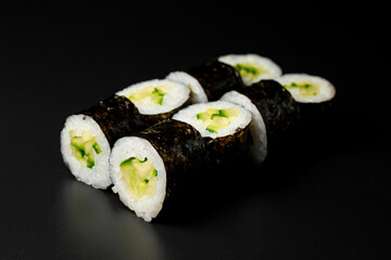 kappa maki sushi rolls with cucumbers and rice wrapped in nori on dark background