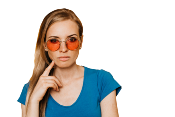 Thoughtful redhead caucasian woman in orange sunglasses dressed in blue t-shirt, with hand on chin, making choice, close up over transparent background with empty space. Doubt concept. Hesitating girl