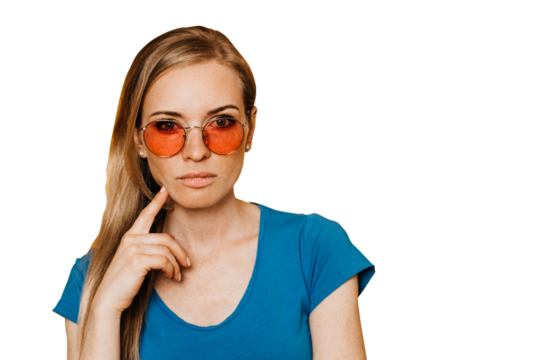 Thoughtful redhead caucasian woman in orange sunglasses dressed in blue t-shirt, with hand on chin, making choice, close up over transparent background with empty space. Doubt concept. Hesitating girl