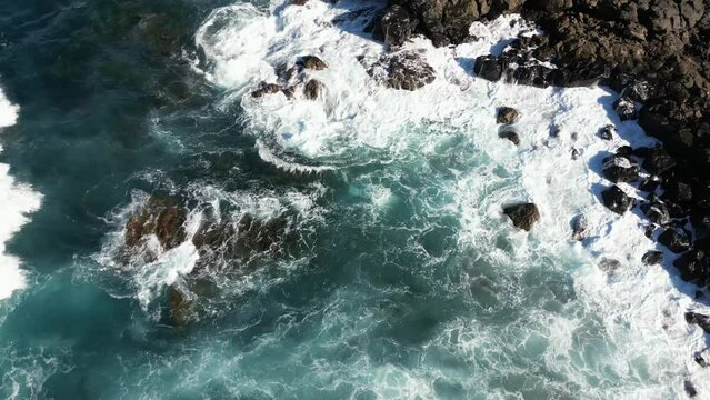 Drone aerial view of the waves of the stormy sea ocean break at the shores on the coast of black lava rocks of volcanic origin in Lanzarote Canary Islands - sea level rise and climate change