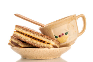 Two mini biscuits with cocoa on a ceramic saucer with a cup, macro, isolated on a white background.