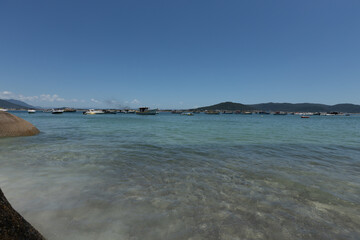 Clear water beach with rocks and mountaisn on an island