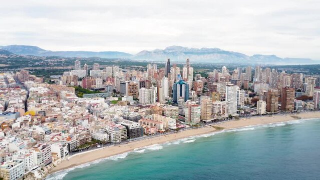 Aerial footage of Benidorm skyline. Skyscrapers and promenade in Levante Beach area. Drone forward creating a beautiful panoramic view of the city. People walking on promenade area.