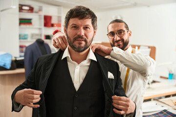 Man putting on suit during fitting session