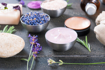 Obraz na płótnie Canvas beauty product samples with fresh purple and blue dried lavenders, bath salts and massage pouches on dark wood table background