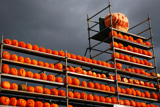 Pumpkins stand high on shelves as storm clouds approach at an autumn festival