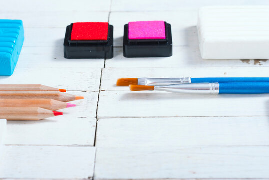 plasticine blocks, ink pads and pencils, brushes on white wood table