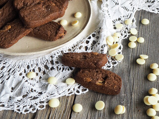 Rebanadas de brownie casero con pepitas de chocolate blanco sobre plato rústico, paño de encaje y mesa de madera