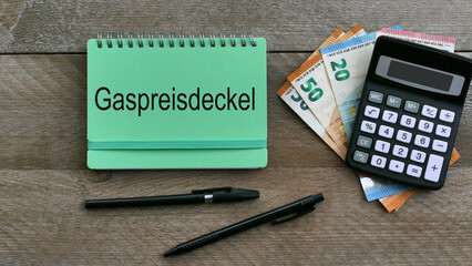 Das Wort Gaspreisdeckel ist auf einem Notizblock mit Taschenrechner und Euro-Banknoten abgebildet.	