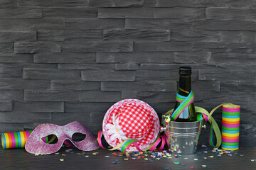 Party und Karneval Hintergrund mit Luftschlangen, Maske, Konfetti, Sekt,und Hut vor einer Mauer mit...