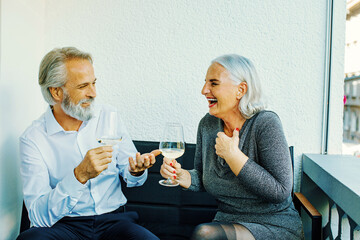 mature senior couple laughing and drinking wine.