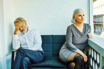 mature couple angry. Woman sitting away from husband after argument