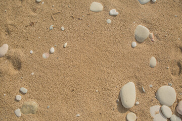 Fototapeta na wymiar Feiner Sand mit hellen und runden Kieselsteinen