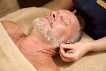 Elderly man receives a wellness relaxing massage