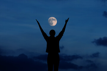 Woman meditating and celebrating under the full moon