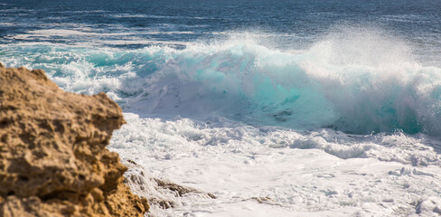Strong wind blows away the spray of a wave