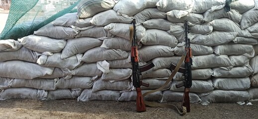 Two Kalashnikovs standing near sandbagged fortifications. AK-74 outdoor