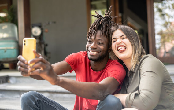 A young and loving multiracial couple taking a playful selfie to share with their friends. Diversity and inclusivity concept