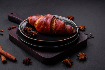 Delicious crispy croissant with chocolate on a black ceramic plate