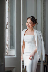 Fototapeta na wymiar a beautiful, confident woman in a white suit at the old window. image of bride