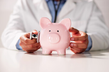 Close-up Of A Doctor's Hand Checking Pink Piggybank