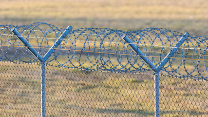Fence with a roll of barbed wire on top at an international border