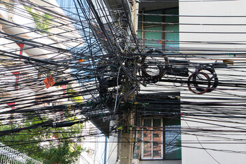 Chaos of cables and wires in Bangkok, Thailand, electric and telephone wires wound on a lamppost