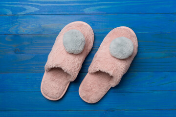 Soft pink slippers on wooden background, top view