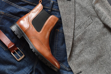 Top view light tan chelsea men boot with dark blue jeans, yellow leather belt and grey tweed blazer. Casual man outlook.