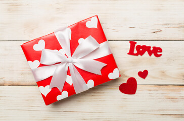 Gift box with hearts on wooden background, top view